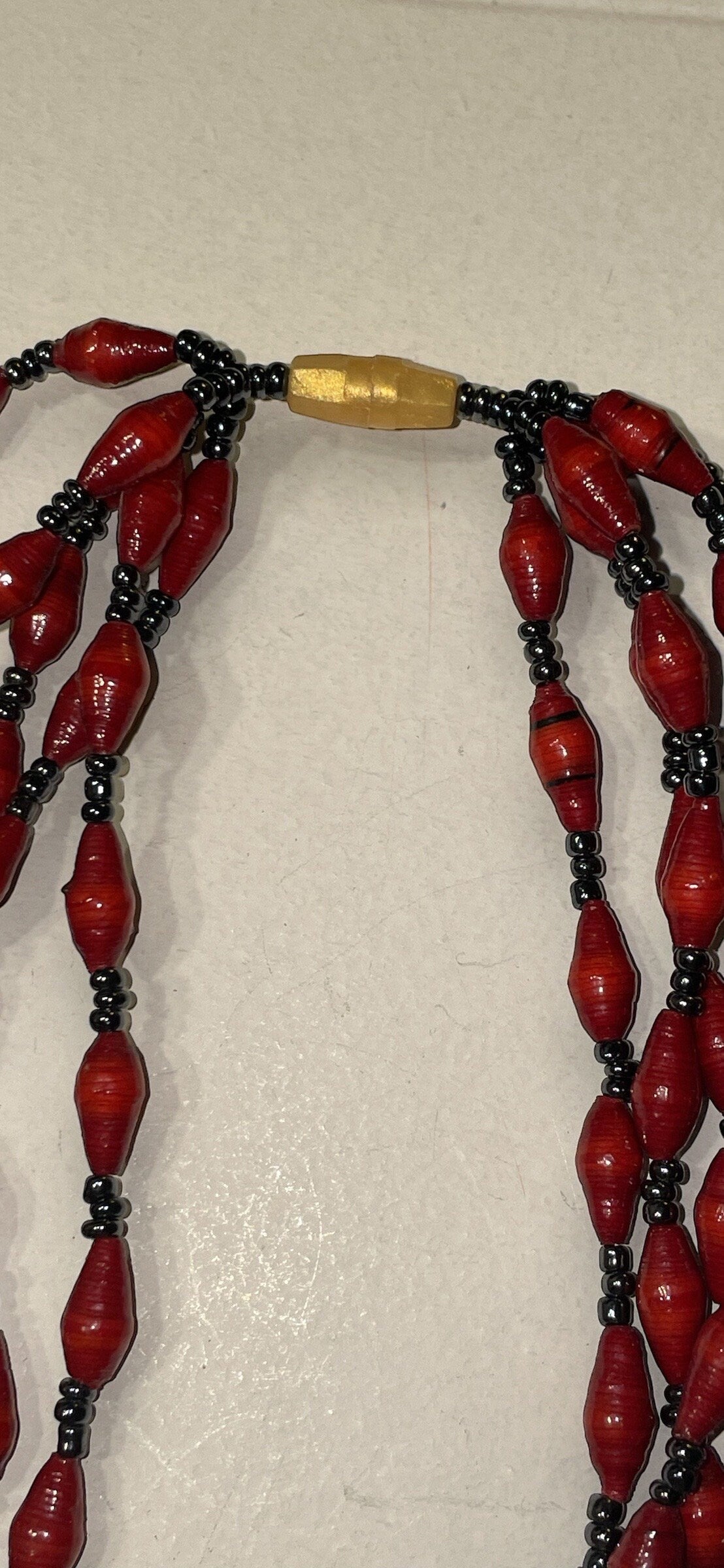 Three-strand necklace made of dozens of itsy bitsy extra tiny little rolled and sealed red paper beads