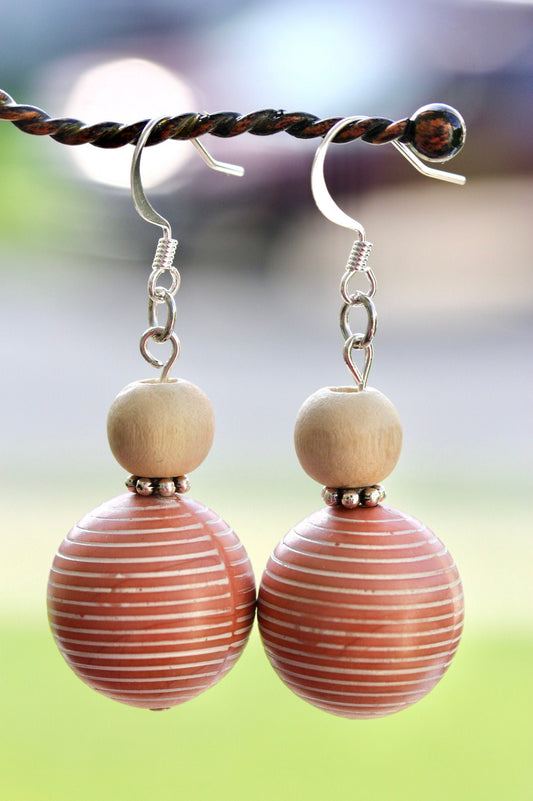 Scandinavian-inspired dangle earrings made of upcycled vintage coral colored striped bead with metal spacers and wood