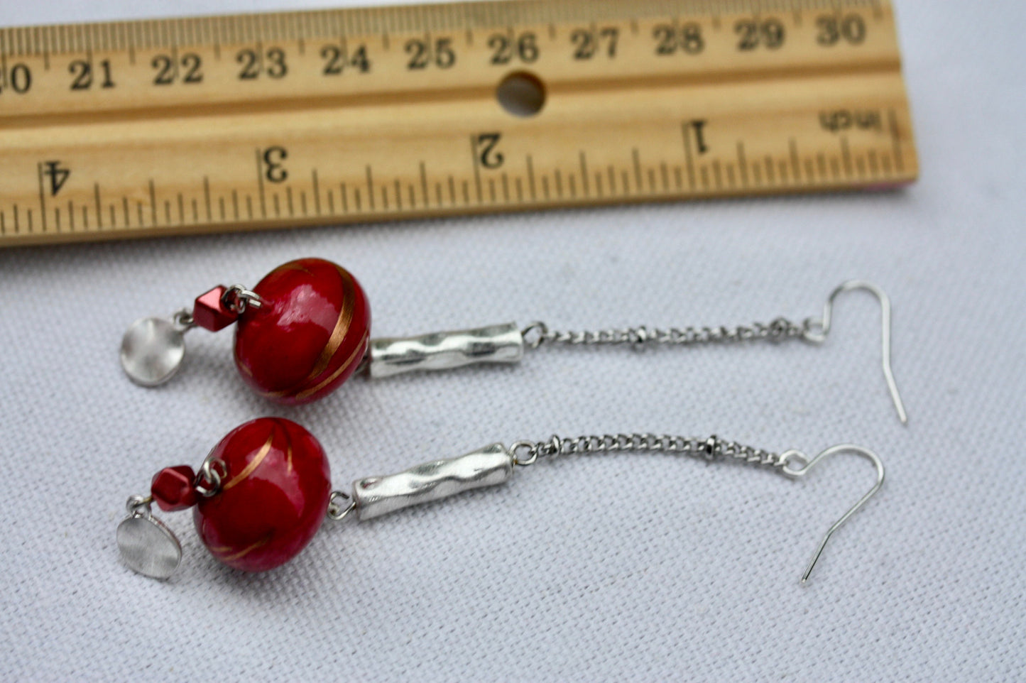 Long mixed material silver chain earrings with silver bars and red dangles, culminating in silver hammered discs