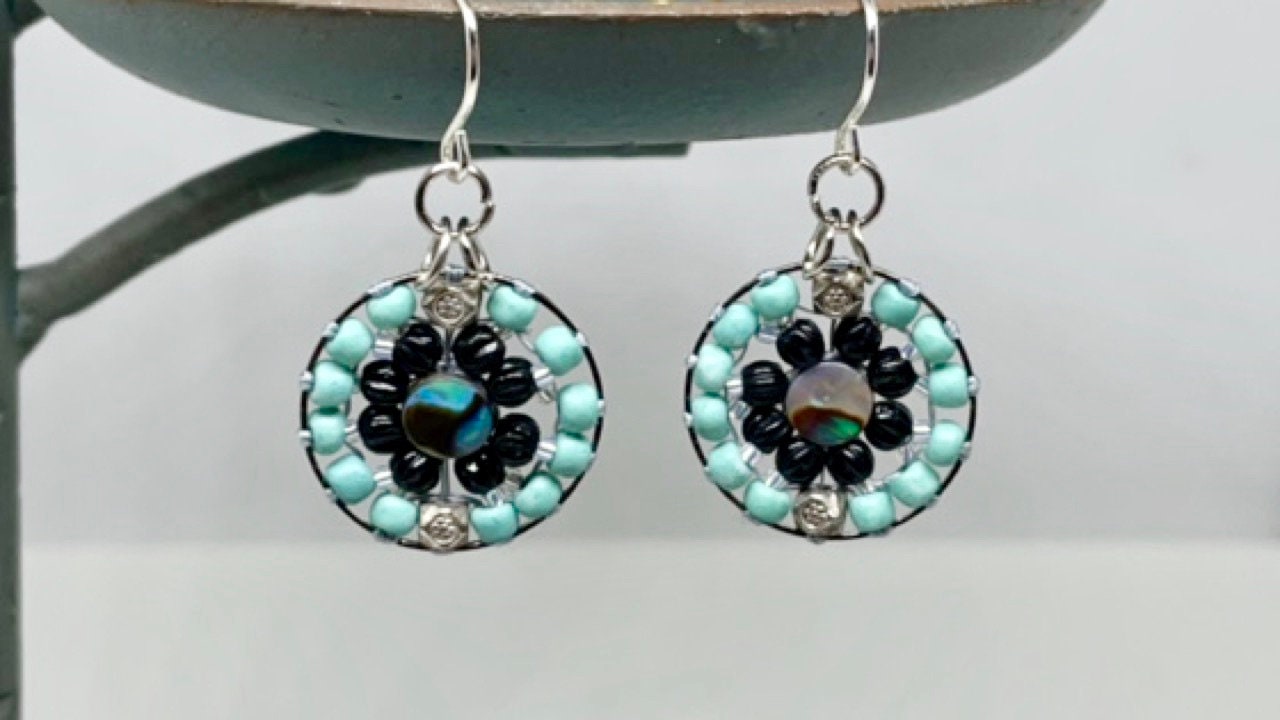 Small dangling handmade turquoise and black beadwork earrings with abalone centers