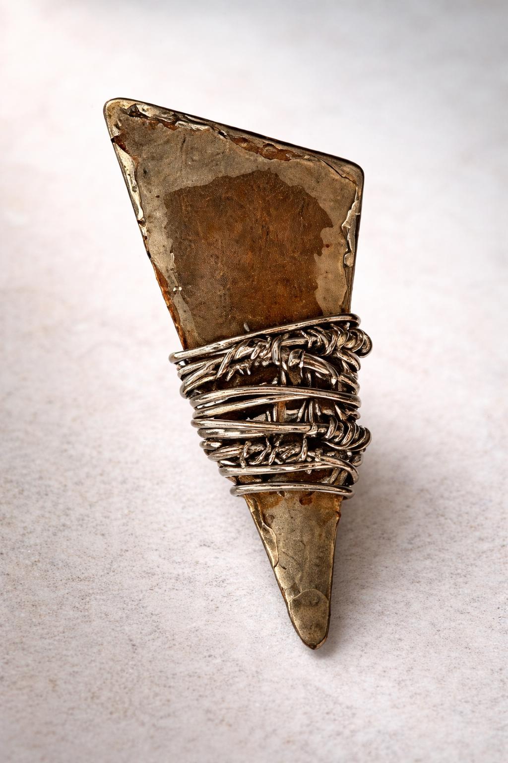 a piece of jewelry with a unique design, including a barbed wire element and a triangular shape.