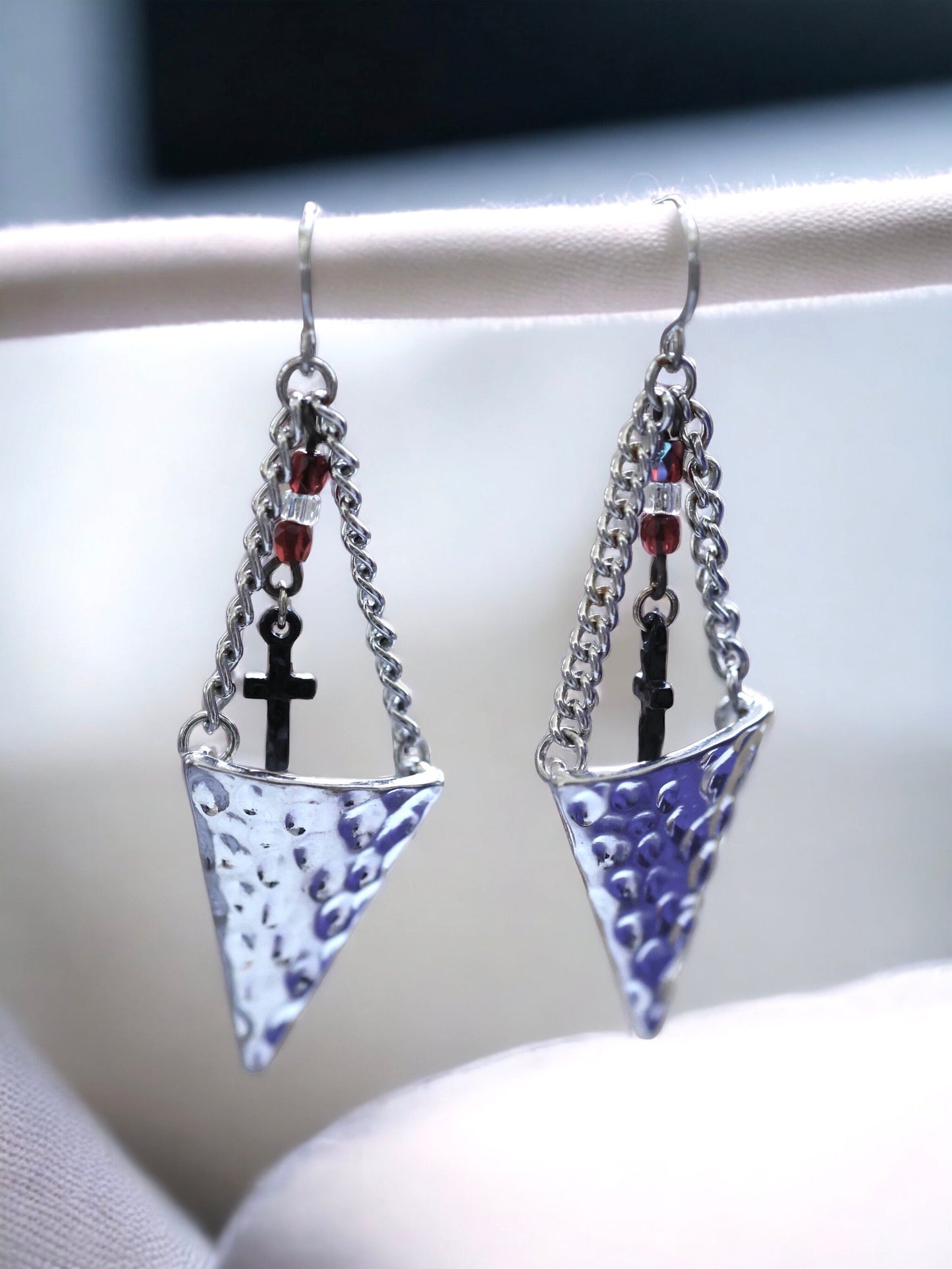 Hammered metal triangular dangle earrings with tiny crosses hanging from glass seed beads