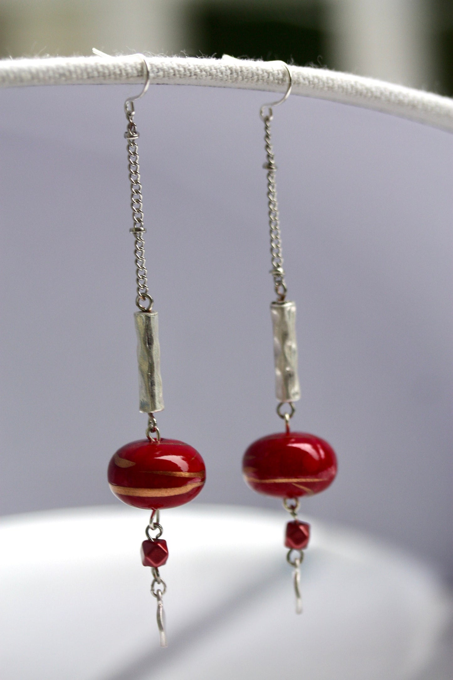 Long mixed material silver chain earrings with silver bars and red dangles, culminating in silver hammered discs