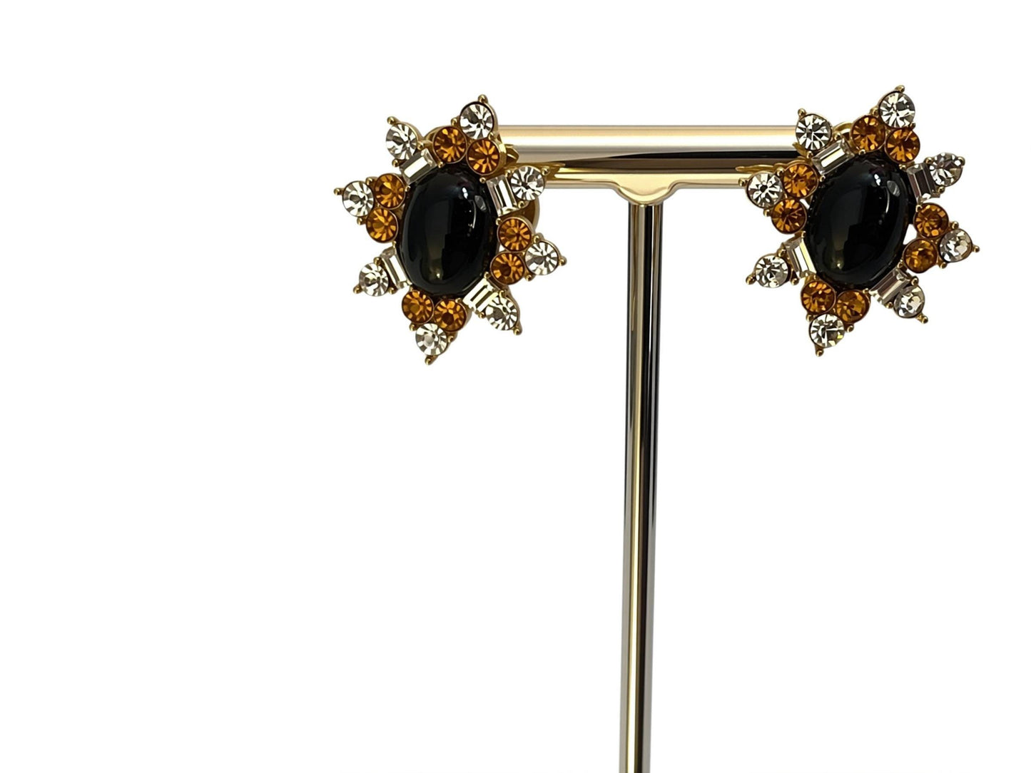 A pair of elegant earrings with a black oval stone surrounded by a floral design and sparkling gemstones.