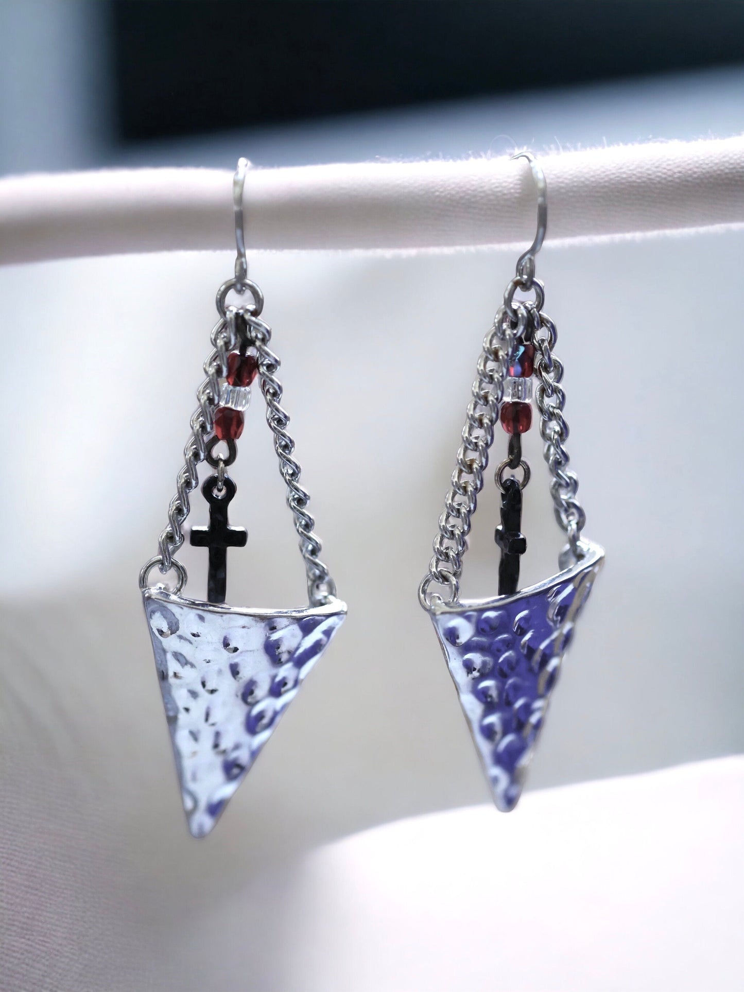 Hammered metal triangular dangle earrings with tiny crosses hanging from glass seed beads
