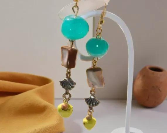 A pair of earrings with turquoise beads, brown and white stones, and small yellow beads hanging from the ear hooks.