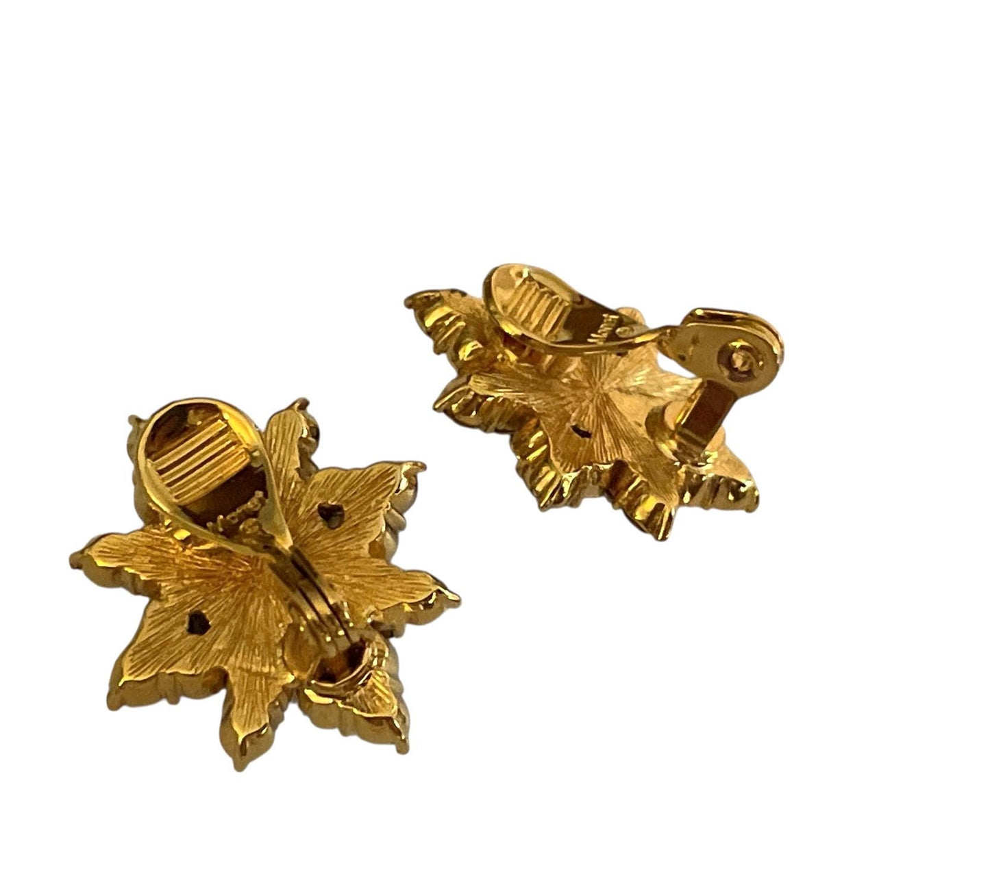 two gold-colored earrings with leaf-shaped designs, one on the left and one on the right.