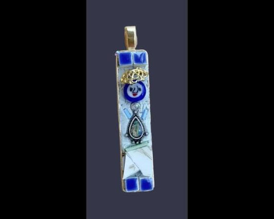 A colorful pendant with a mix of blue, white, and gold elements, including a small blue flower, a gold crown, and a silver teardrop-shaped charm.