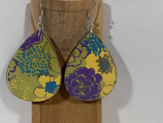 A pair of colorful earrings with floral designs, hanging from a hook against a plain background.
