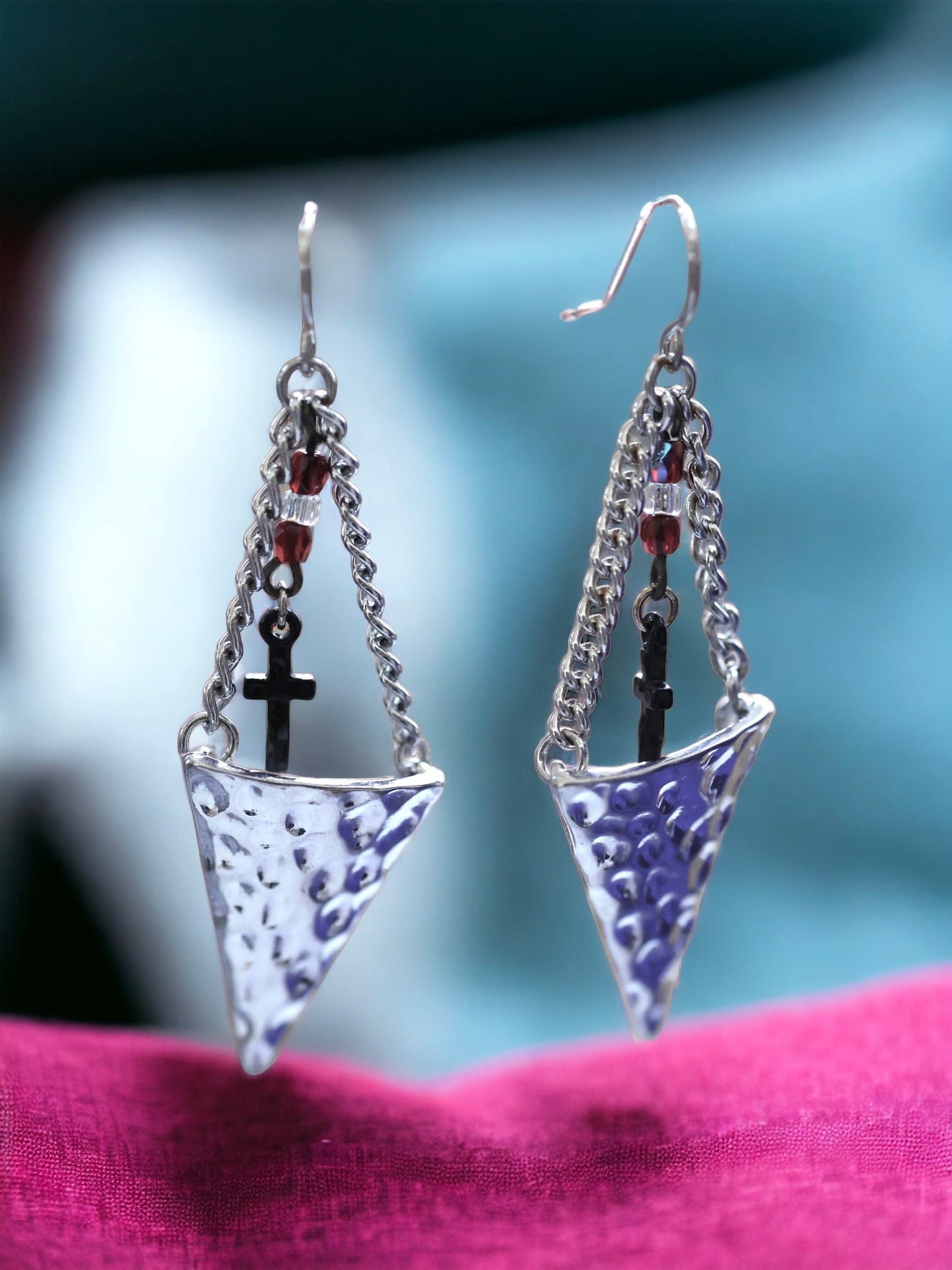 Hammered metal triangular dangle earrings with tiny crosses hanging from glass seed beads