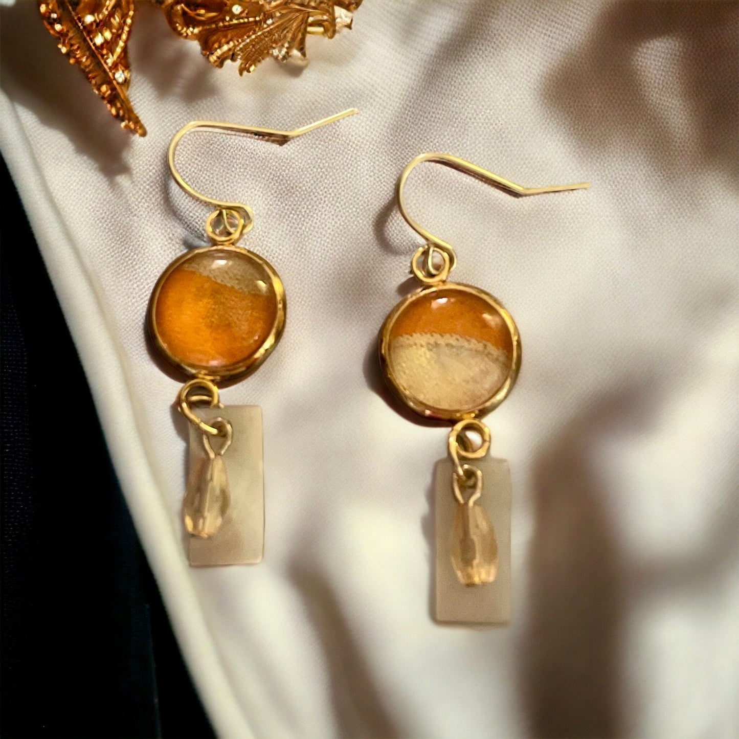 Orange and cream fabric inlaid glass cabochon earrings with rectangular mother of pearl and pale orange dangles
