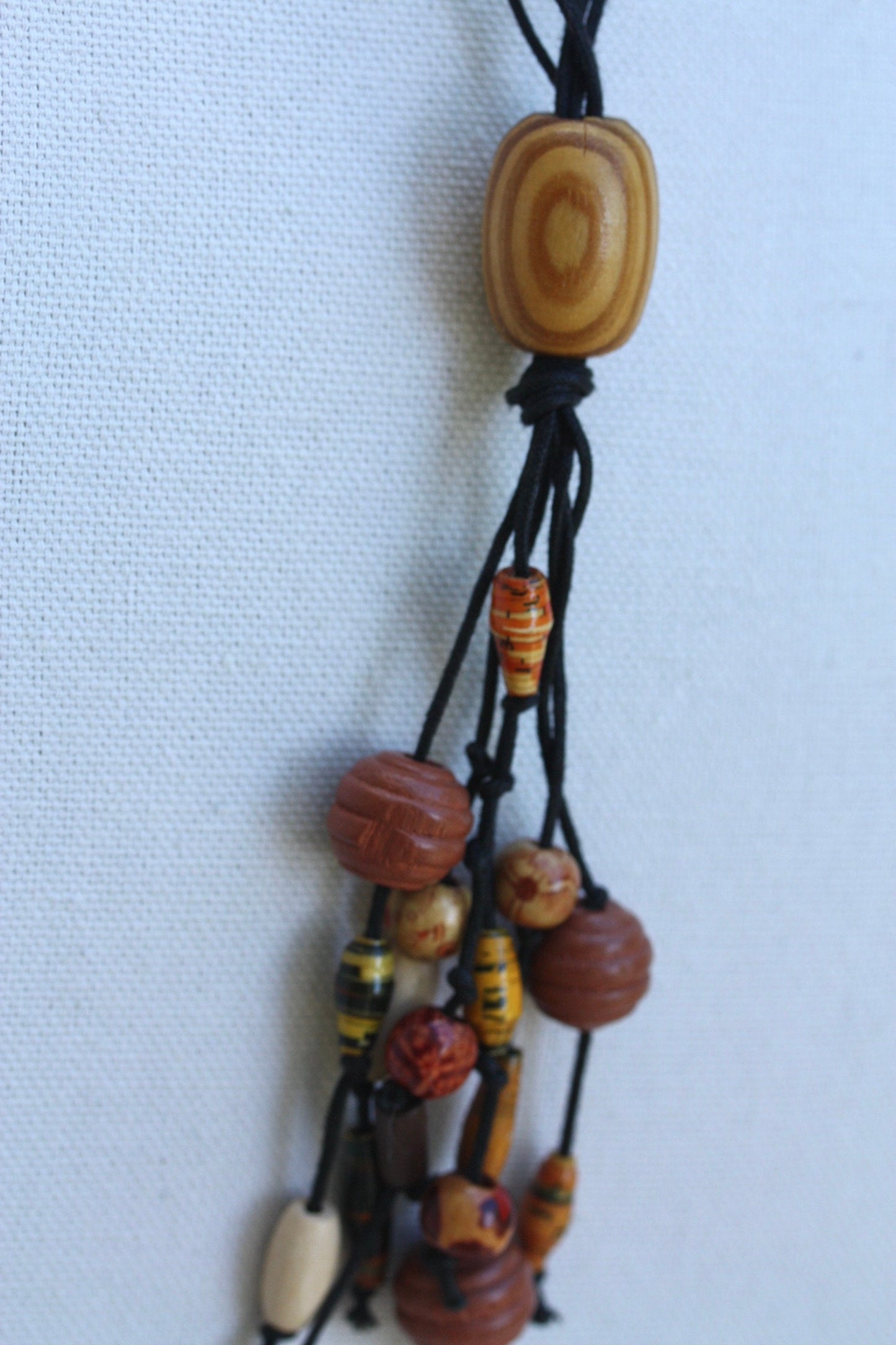 Long vintage wood, paper, glass mixed material vintage tassel necklace on black satin