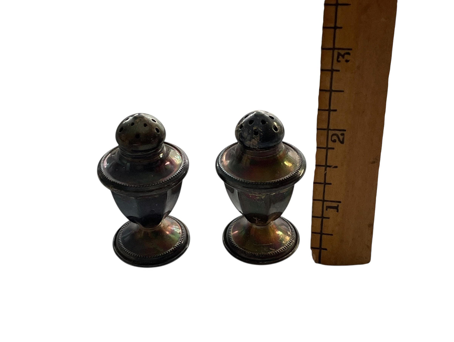 Two silver salt and pepper shakers next to a ruler for size comparison.