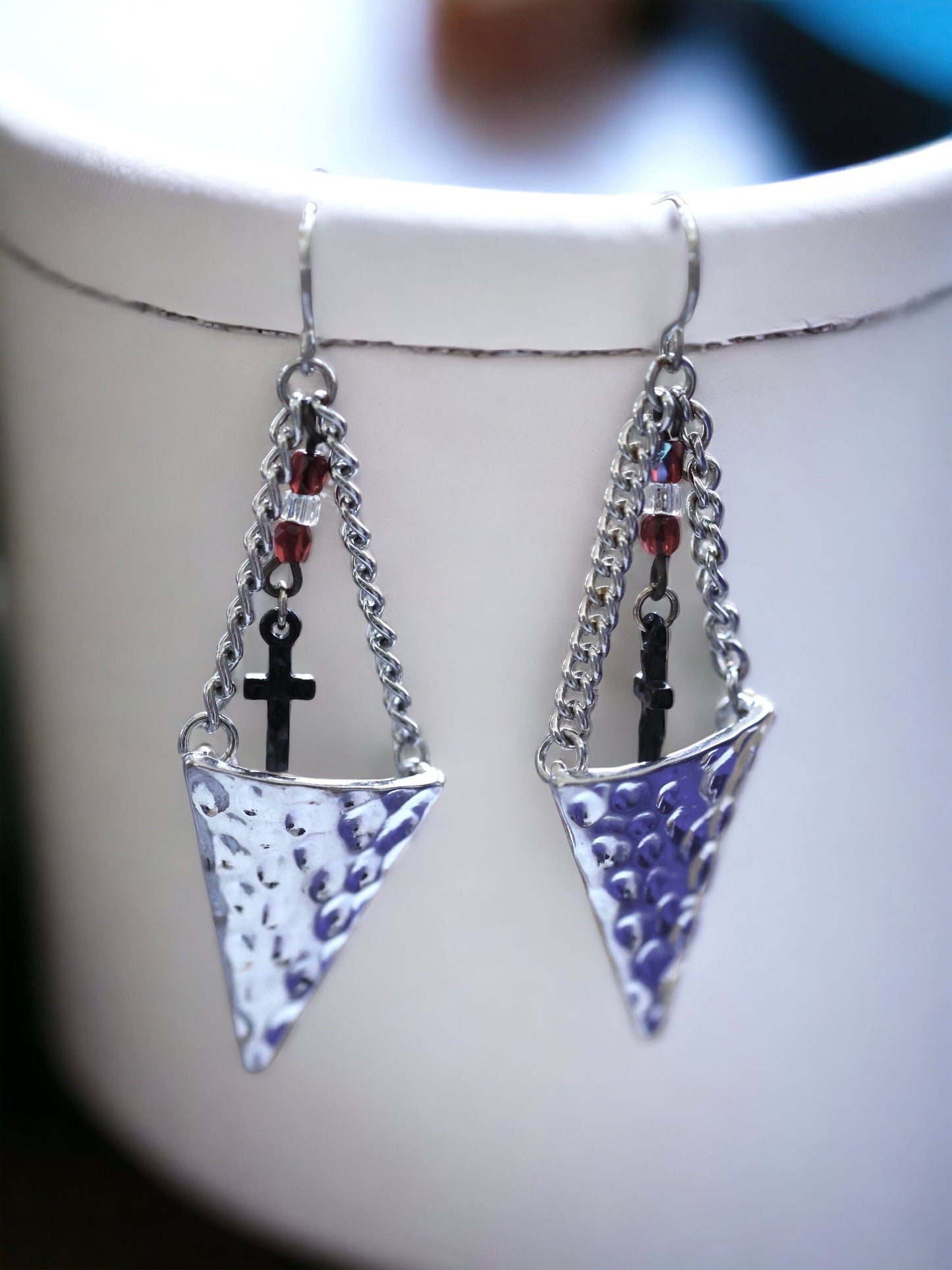 Hammered metal triangular dangle earrings with tiny crosses hanging from glass seed beads