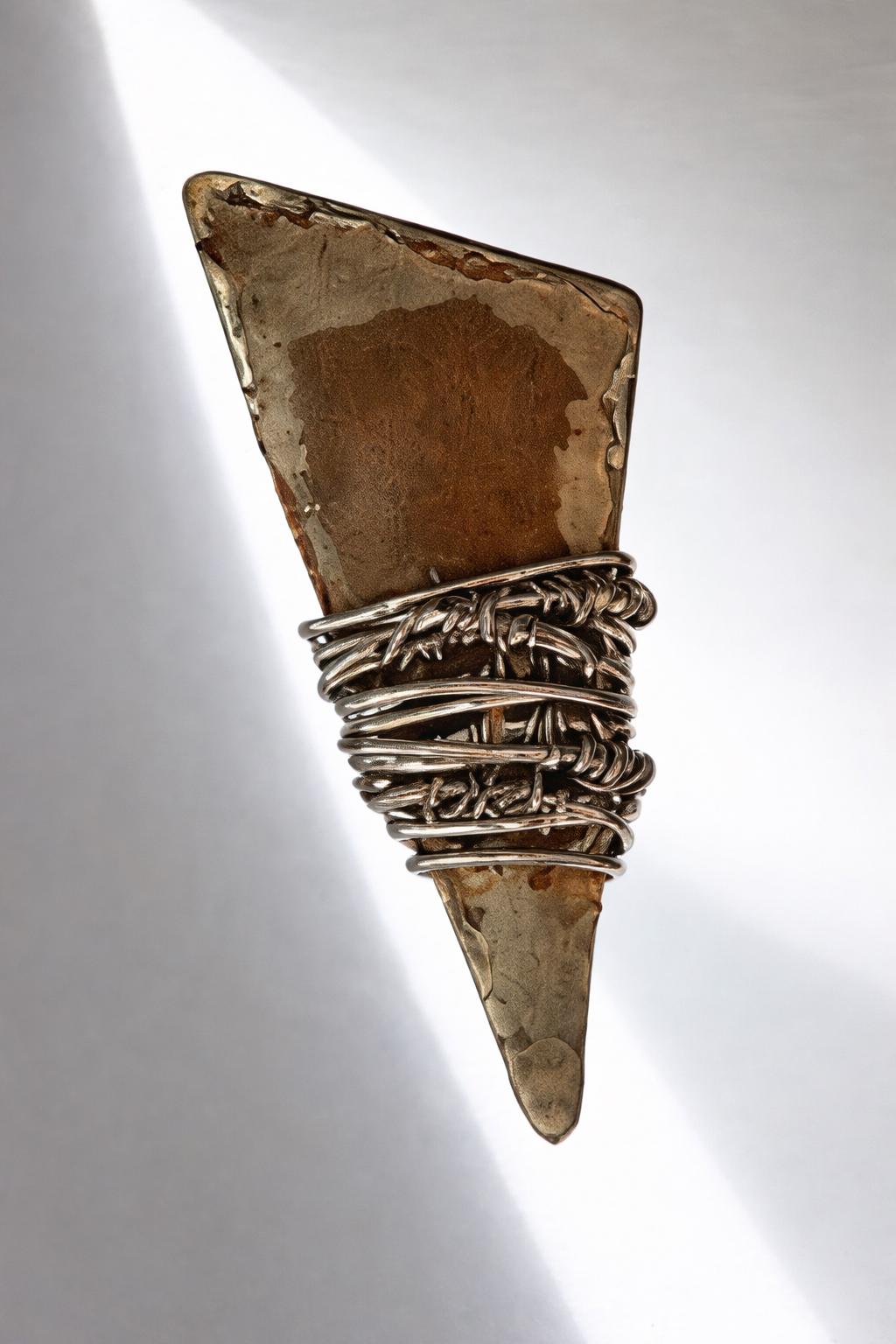 a piece of jewelry with a unique design, including a triangular shape and a combination of metal and wood elements.