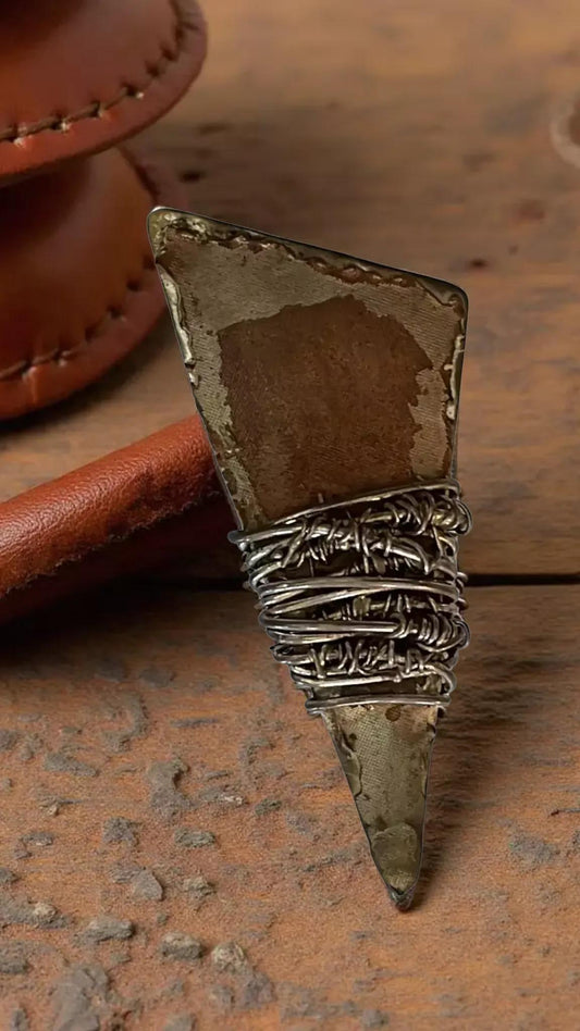 a close-up view of a metal object with a twisted, rusted appearance, resting on a wooden surface.