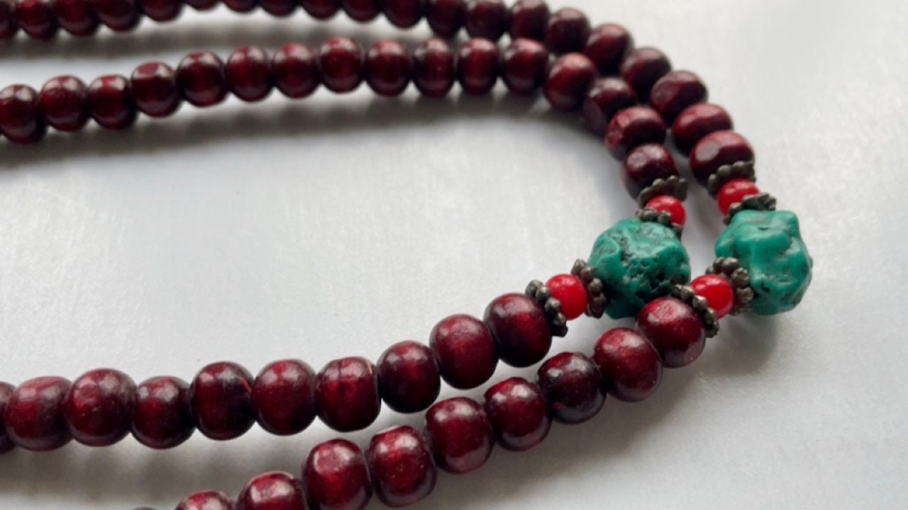 Long turquoise and wood vintage beaded necklace on red satin