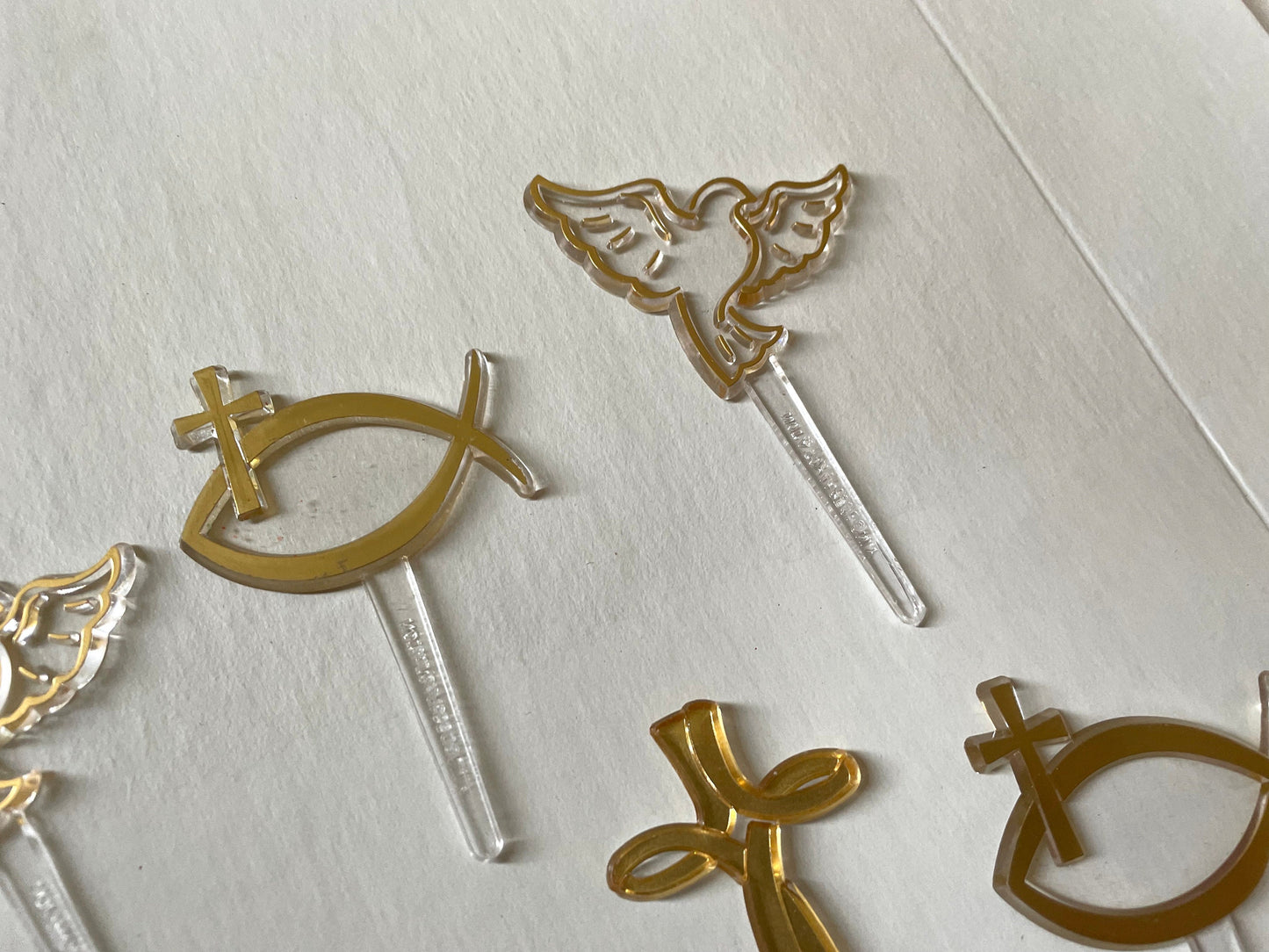 Mix of clear and gold plastic cake toppers - cross, fish and dove