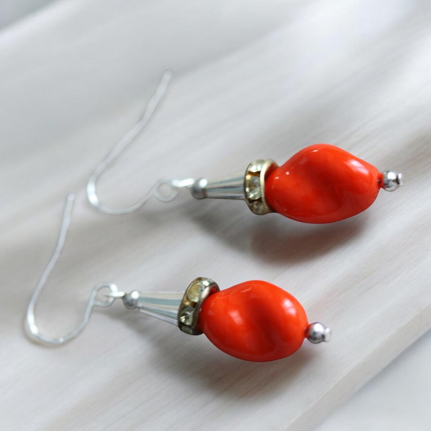 Unique dangle earrings featuring orange free form slightly twisted vintage glass, metal cone beads and rhinestone spacers
