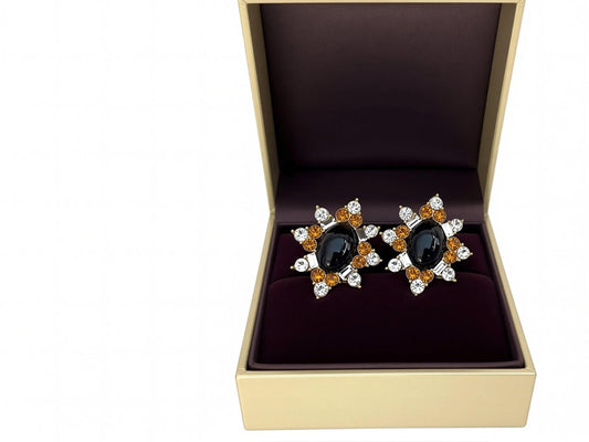 A pair of earrings with a black oval stone surrounded by a floral design and small, round, and clear gemstones.