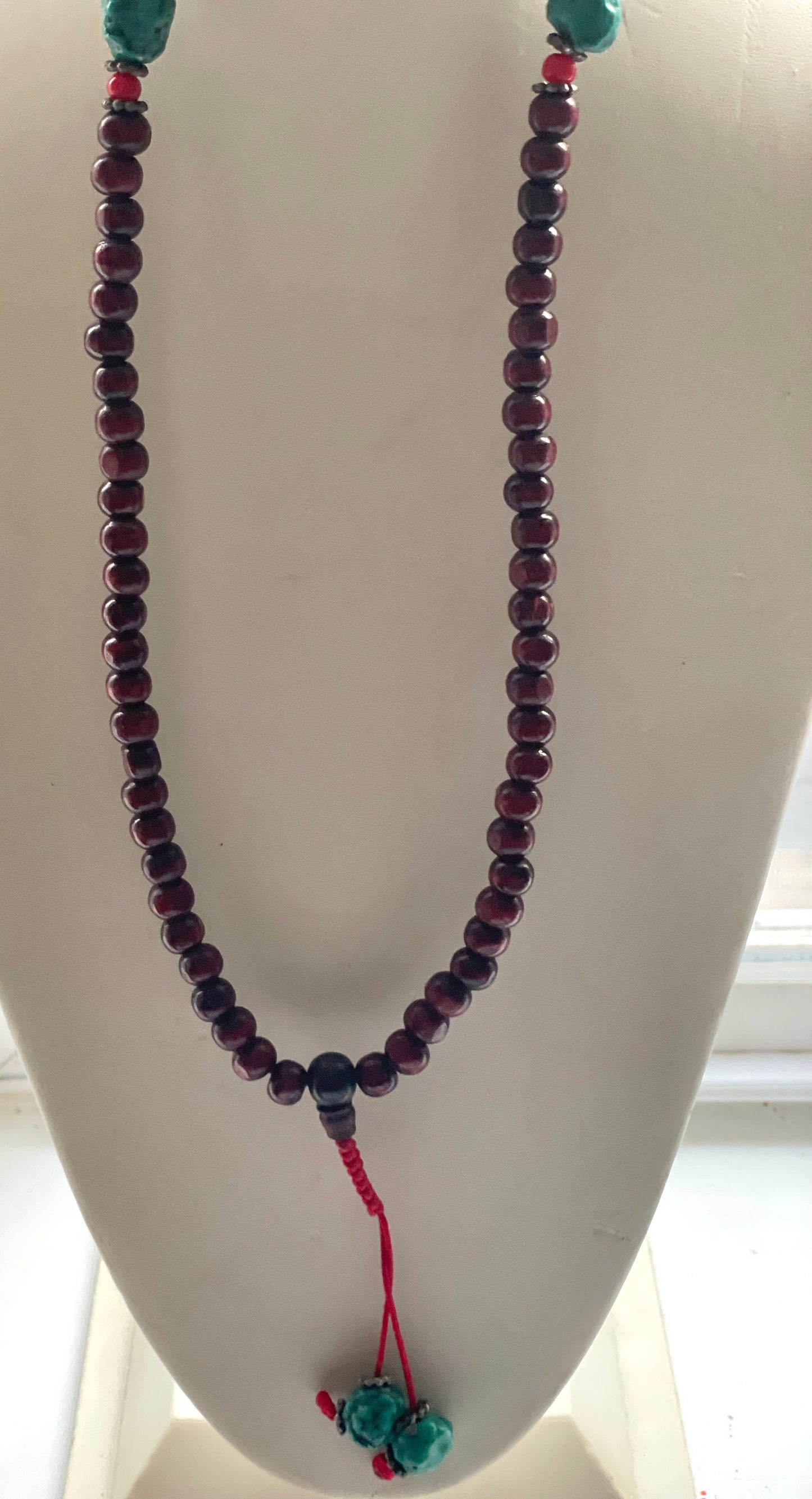 Long turquoise and wood vintage beaded necklace on red satin