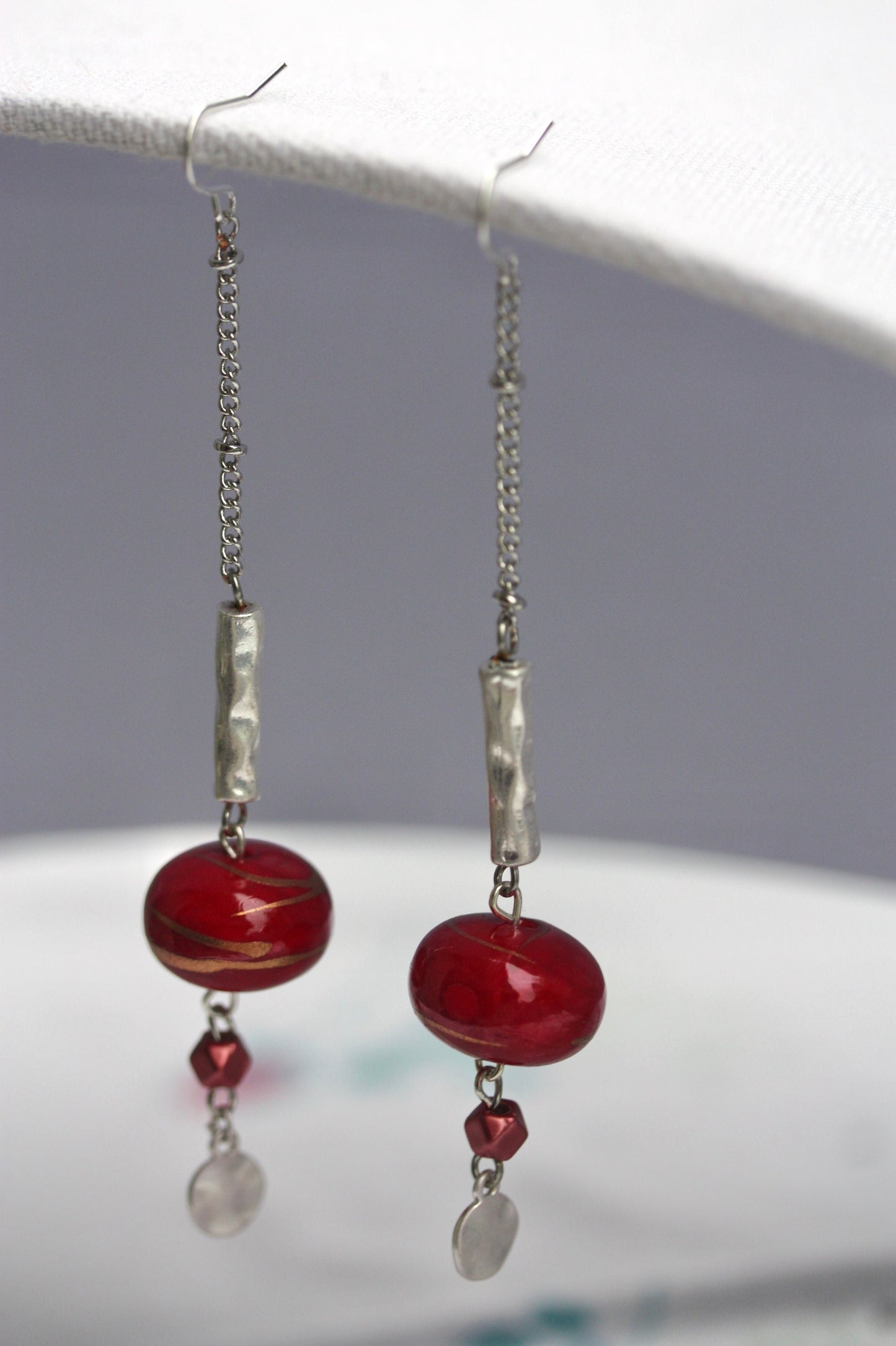 Long mixed material silver chain earrings with silver bars and red dangles, culminating in silver hammered discs