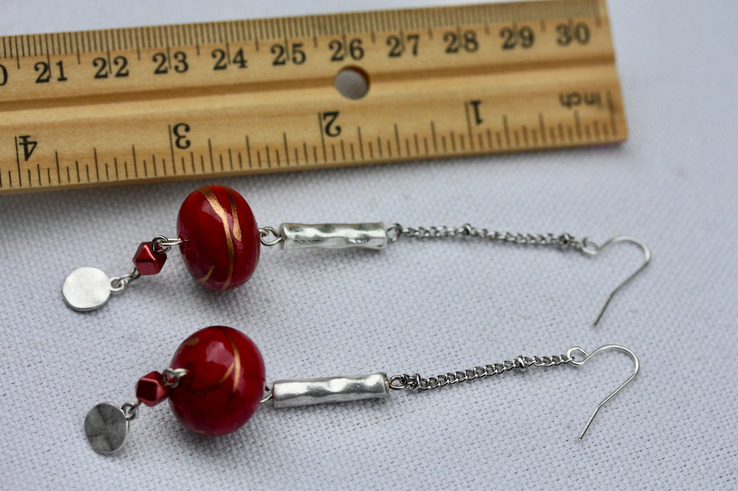 Long mixed material silver chain earrings with silver bars and red dangles, culminating in silver hammered discs