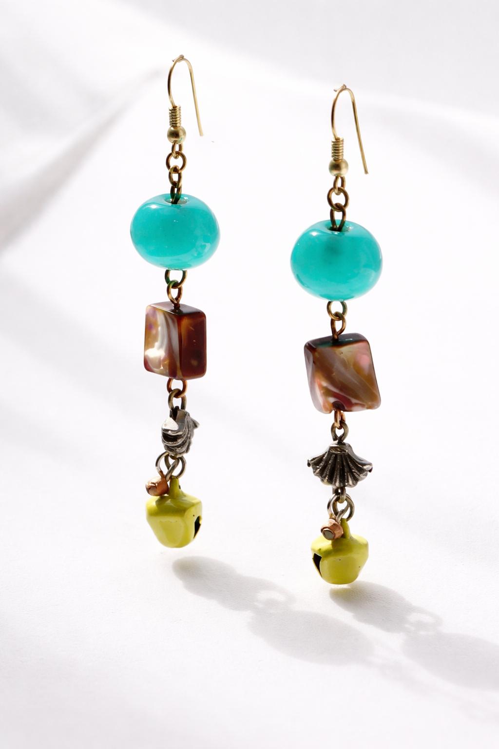 A pair of earrings with turquoise beads, square-shaped stones, and small bells hanging from the earrings.