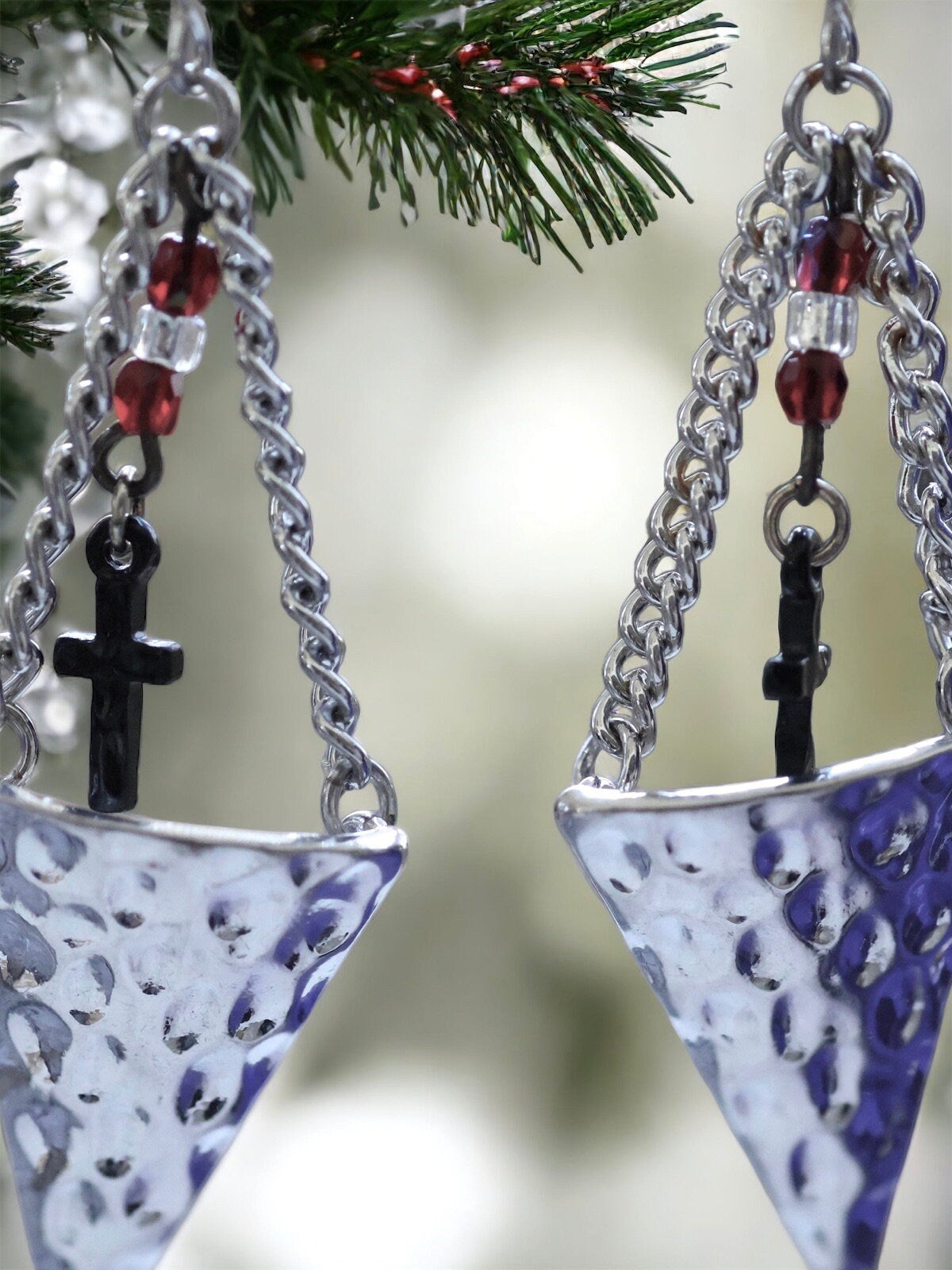 Hammered metal triangular dangle earrings with tiny crosses hanging from glass seed beads
