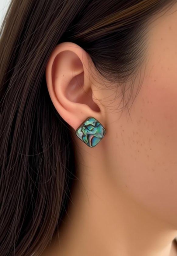 A close-up view of a person's ear wearing a pair of earrings with a colorful, abstract design.