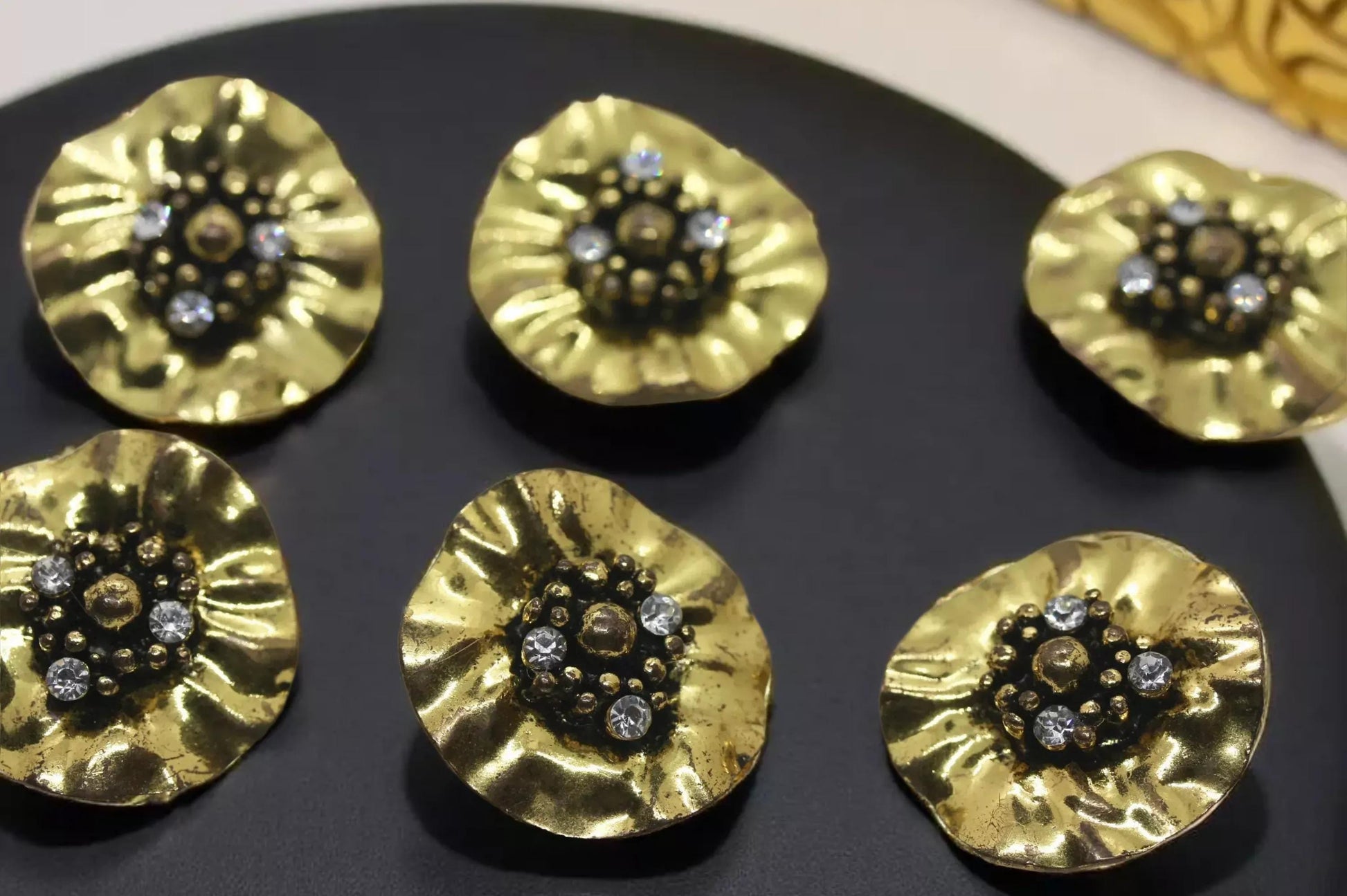 a collection of ornate, golden-colored metal earrings with small gemstones or crystals set in the center.